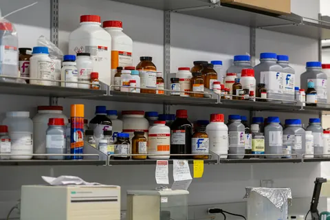 Cheminių reagentų buteliai laboratorijos lentynose